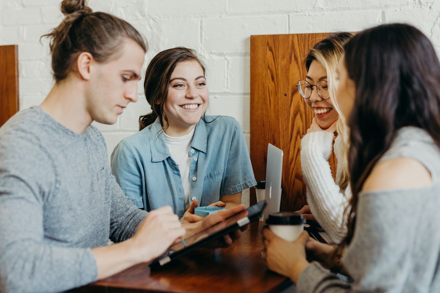 A group of students chatting over coffee with a laptop on the table